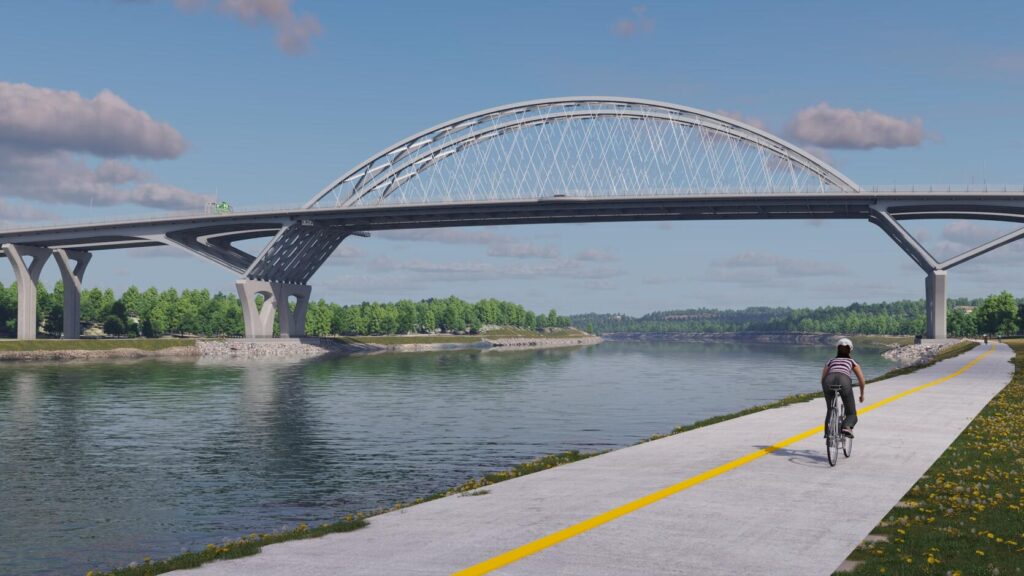 The new Sagamore Bridge spanning the Cape Cod Canal, seen from the canal path, with a cyclist riding in the foreground.